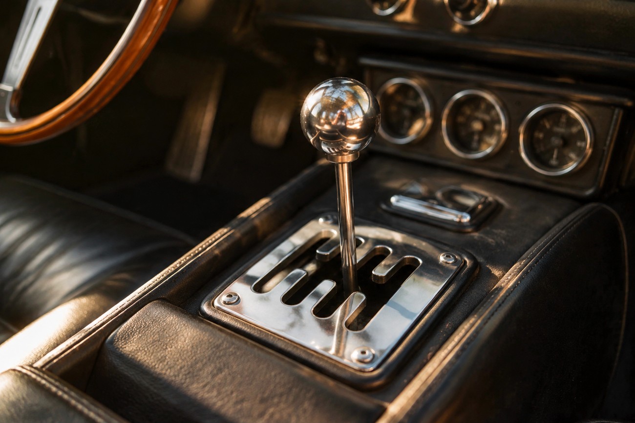Close-up of a polished metal gated manual gear shifter and spherical knob inside a classic Ferrari Mondial interior