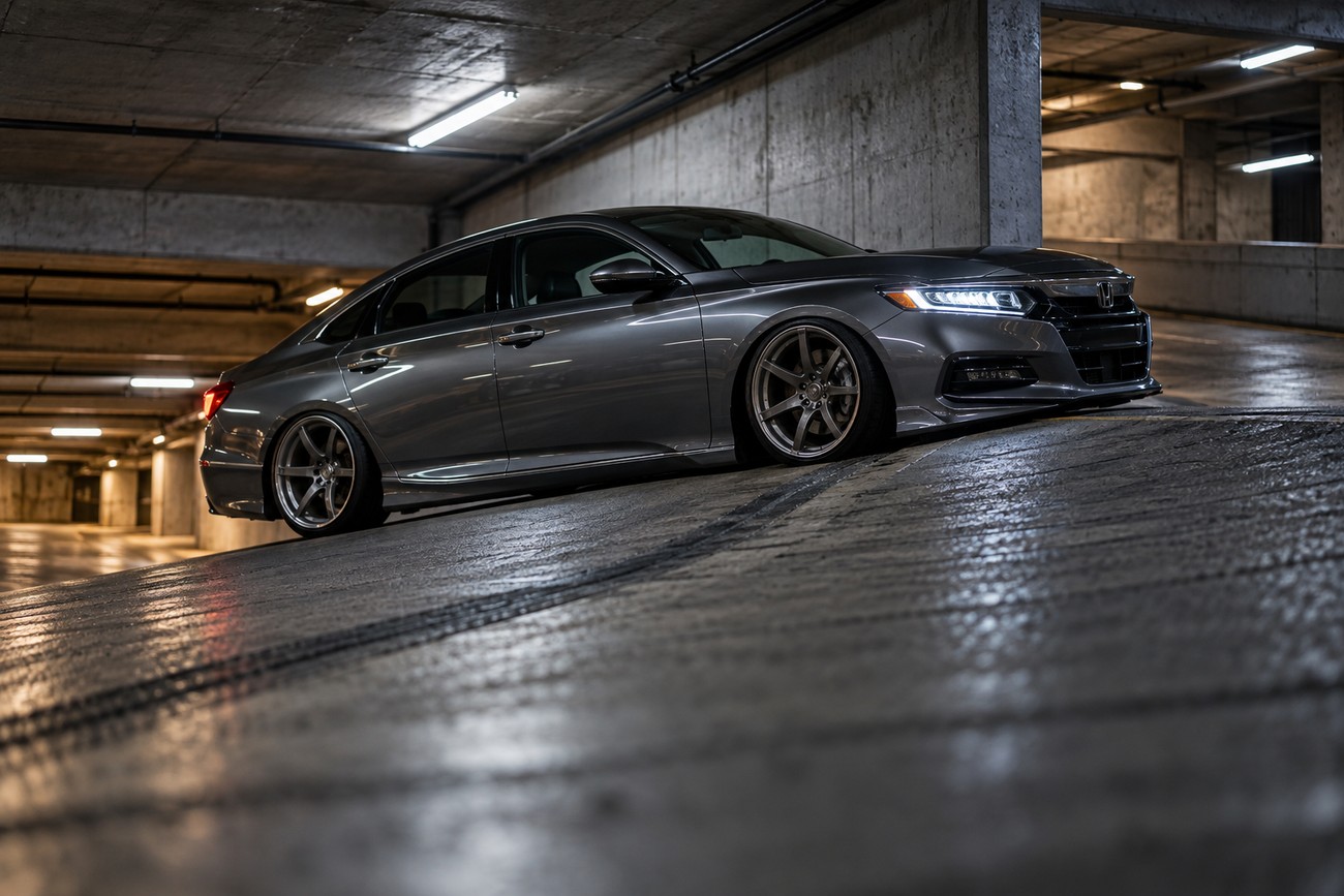 A sleek gray lowered Honda Accord slowly driving down a concrete ramp in an underground parking garage