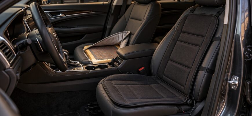 A black heated seat pad attached to a leather car seat alongside a retrofit heating element kit on another seat
